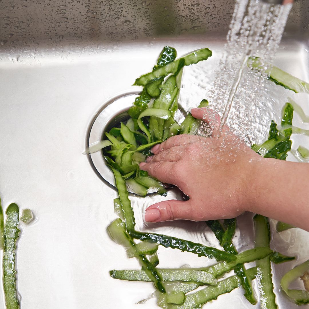 Someone cramming food scraps in a garbage disposal